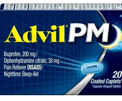 A person asleep on a couch with a pack of Advil PM and a pack of Zyrtec on a nearby table