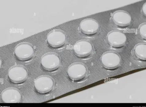 Two different oral antihistamine tablets in their blister packs beside a glass of water