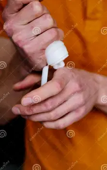 Person applying moisturizing emollient cream to the back of a dry hand with visible flaking skin