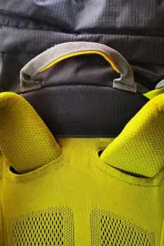 Person wearing a backpack with shoulder straps pressing against the upper back during physical activity
