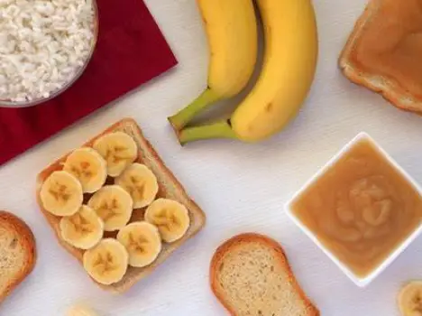 White toast, plain boiled rice, sliced banana, and a glass of oral rehydration solution on a table