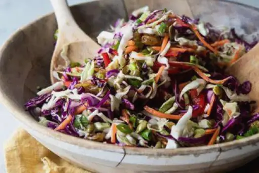 Cabbage used in four dishes: green and red cabbage coleslaw, Napa cabbage in a stir-fry with vegetables, Savoy cabbage leaves rolled as stuffed cabbage, and sauerkraut served as a condiment beside a main dish