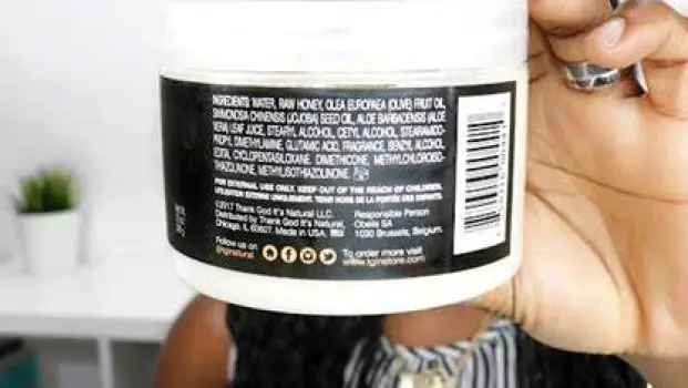 Close-up of a person reading the ingredient list on the back of a hair smoothing product bottle