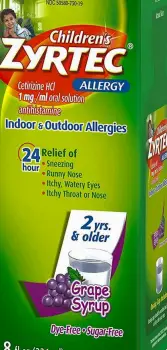 Children's cetirizine syrup bottle next to a chewable allergy tablet