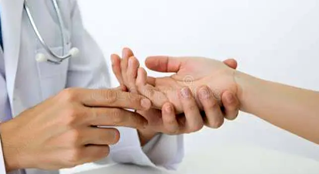Clinician closely examining the skin on a patient's hand during a medical evaluation