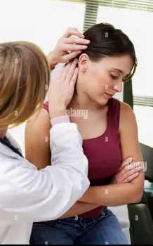 A healthcare provider using a bright light to closely examine a patient's scalp and hair part during a clinical assessment.