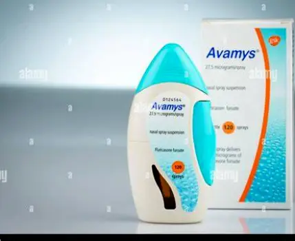 Clear plastic nasal spray bottle with a cap on a plain background