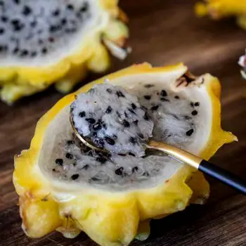 Yellow dragon fruit halved lengthwise with visible white flesh and black seeds