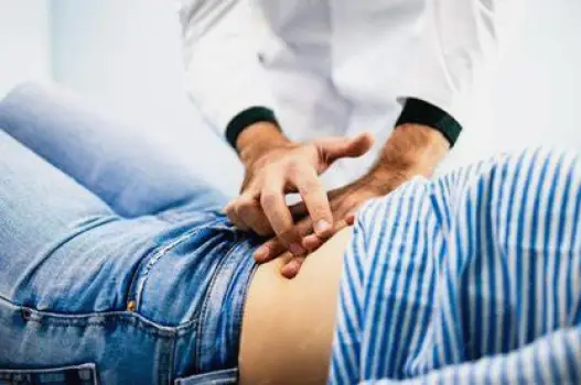 Clinician pressing on a patient's upper-right abdomen during a physical examination