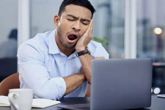 Person yawning at a desk with visible drowsiness