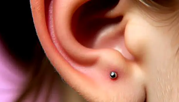Close-up of a person's ear with a piercing through the fleshy earlobe