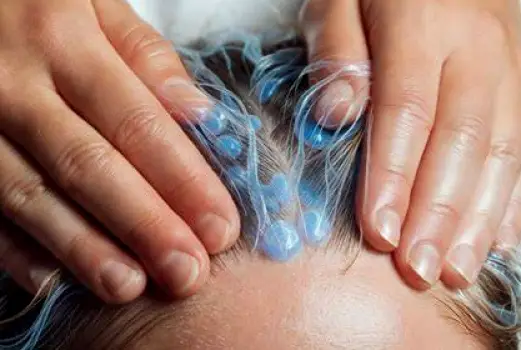 Close-up of a person using fingertips to massage the scalp along the top of the head