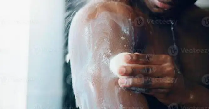 Person gently washing their shoulder in the shower using a soft white cloth and a mild liquid cleanser.