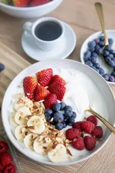 A bowl of thick Greek yogurt with a spoon resting in its dense, creamy surface
