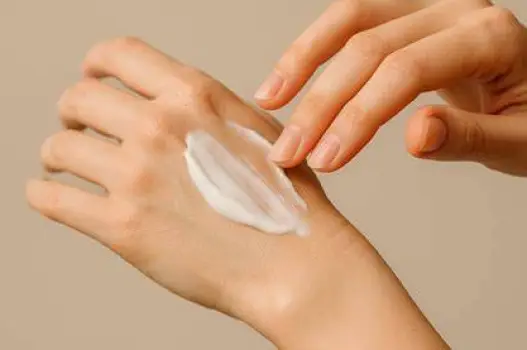 Hand applying a thin layer of antifungal cream to the skin of a foot