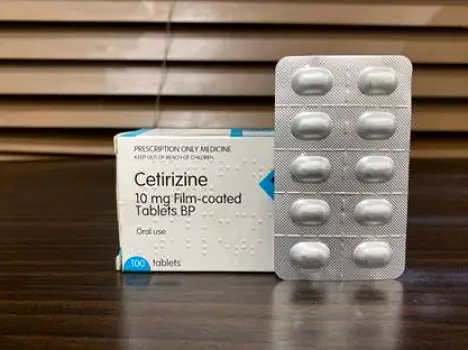 A small white ibuprofen tablet and an oval white cetirizine tablet resting on a plain surface