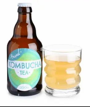 A bottle of kombucha beside a glass of carbonated tea beverage
