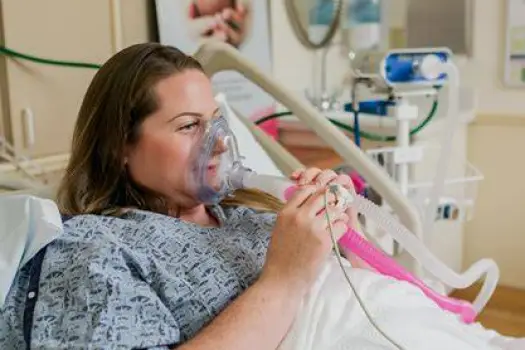 Person inhaling nitrous oxide through a mask held to their face during a contraction, showing the flexible use of laughing gas for anxiety relief during labor.