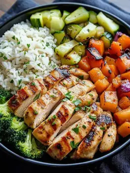 Bowl of parboiled rice topped with mixed vegetables and grilled chicken
