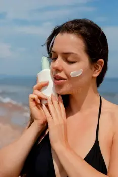 Person applying sunscreen to their face outdoors