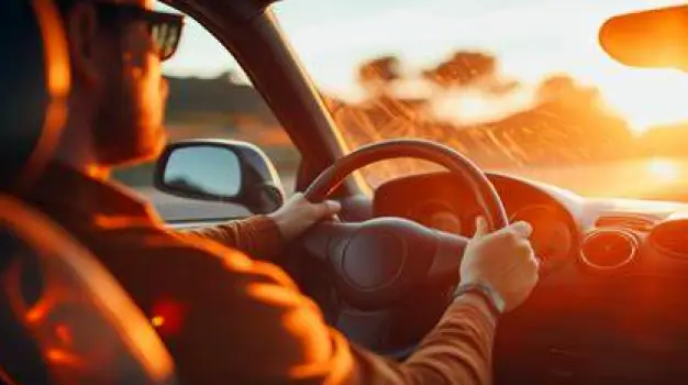 A person looking forward while holding the steering wheel of a car during the day