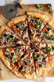 Close-up of a pizza with tomato sauce, melted cheese, and vegetable toppings