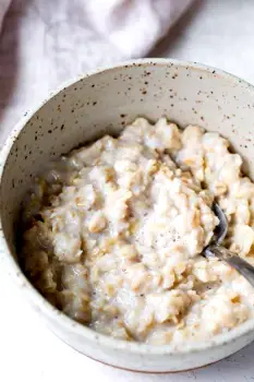 A bowl of plain oatmeal cooked in water with no toppings cooling on a kitchen counter