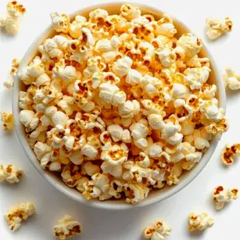 Close-up of plain, unpopped yellow popcorn kernels resting in a simple ceramic bowl.