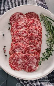 Small portion of thin salami slices placed on a balanced plate of pasta, vegetables, and a side salad