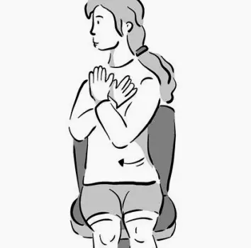 Person sitting upright on a chair, slowly rotating the torso to one side with a hand resting on the back of the chair