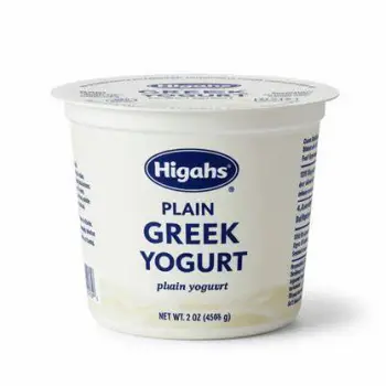 A person taking a small spoonful of Greek yogurt from a bowl beside a notepad on a kitchen table