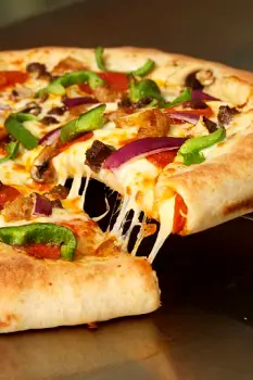 Two pizzas on a table: a thin-crust pizza with vegetable toppings and moderate cheese next to a stuffed-crust pizza with extra cheese